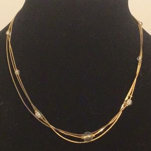 Gold tone three strand necklace with clear beads